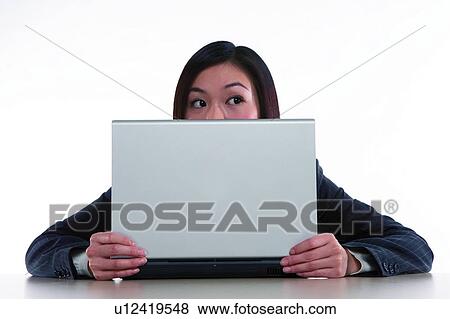 Stock Photo - Young woman in business suit, sitting, holding notebook in front, looking to the right. Fotosearch