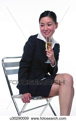 Stock Photo - Young woman in business suit, sitting, holding a glass of wine. Fotosearch