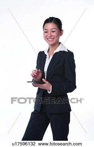 Stock Image - Young woman in business suit, standing, smiling. Fotosearch