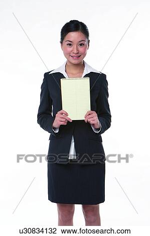 Young woman in business suit, standing, holding notebook in the middle View Large Photo Image Stock Image - Young woman in business suit, standing, holding notebook in the middle. Fotosearch