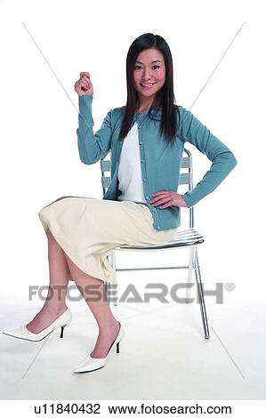 Young woman sitting on chair and raising one hand View Large Photo Image Stock Image - Young woman sitting on chair and raising one hand. Fotosearch
