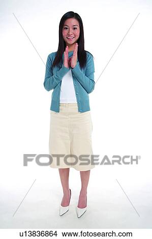 Picture - Young woman standing, looking at camera and clapping hands, full length. Fotosearch