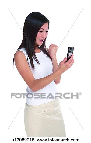 Stock Photo - Young woman standing, looking at mobile phone and folding hand in fist. Fotosearch