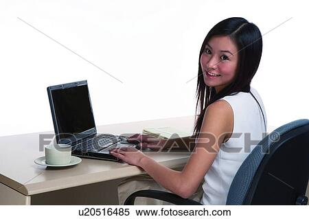 Young woman working, looking back, in office environment View Large Photo Image Stock Photography - Young woman working, looking back, in office environment. Fotosearch