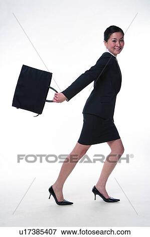 Stock Photo - Young woman in business suit, carrying briefcase, running. Fotosearch