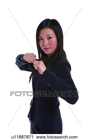 Stock Image - Young woman in business suit, standing in fighting position. Fotosearch