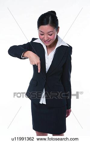 Stock Image - Young woman in business suit, standing, pointing down. Fotosearch