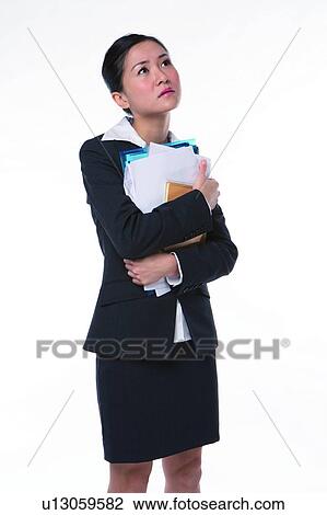 Young woman in business suit, standing, holding documents, thinking View Large Photo Image Stock Image - Young woman in business suit, standing, holding documents, thinking. Fotosearch