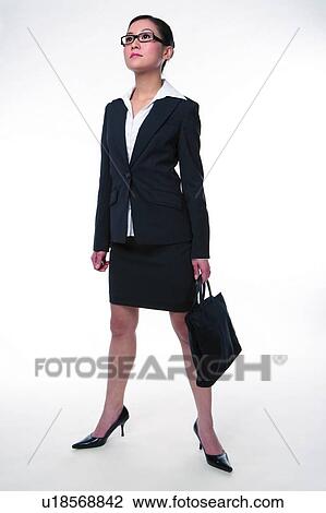 Stock Image - Young woman in business suit, standing, looking up confidently. Fotosearch