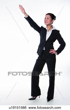 Young woman in business suit, standing, stretching arm, saying "Hi" View Large Photo Image Stock Photograph - Young woman in business suit, standing, stretching arm, saying "Hi". Fotosearch