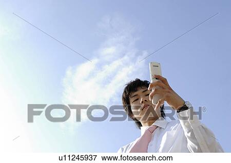 Stock Photo - Businessman to see a cell phone. Fotosearch