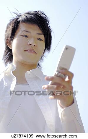 Man looking at a cell phone View Large Photo Image Stock Photo - Man looking at a cell phone. Fotosearch