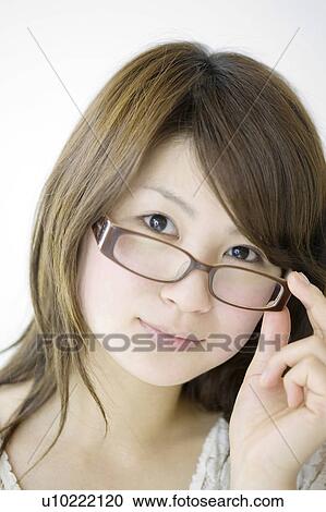 Stock Image - Woman putting on glasses. Fotosearch
