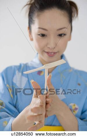 Stock Image - Yukata woman who plays with the bamboo dragonfly. Fotosearch