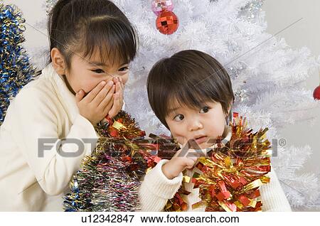 Stock Photo - Brother and sister in front of Christmas tree. Fotosearch