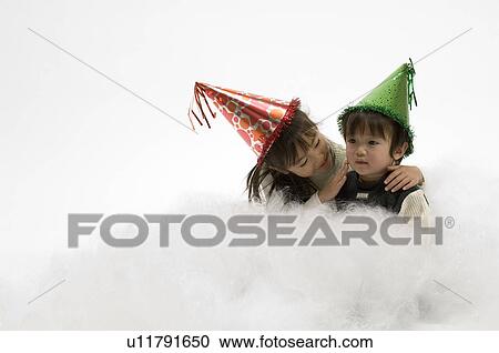 Stock Image - Brother and sister wearing party hats. Fotosearch