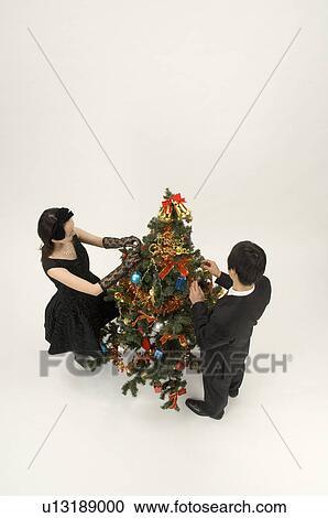 Stock Image - Couple decorating Christmas tree. Fotosearch
