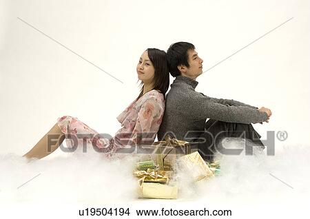 Picture - Couple sitting next to Christmas presents. Fotosearch