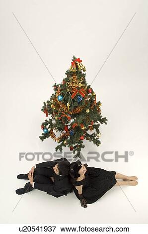 Couple sitting next to Christmas tree View Large Photo Image Stock Photo - Couple sitting next to Christmas tree. Fotosearch
