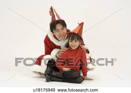 Stock Photo - Father in Santa outfit sitting with daughter. Fotosearch