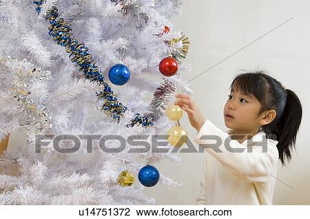 Girl decorating Christmas tree View Large Photo Image Stock Image - Girl decorating Christmas tree. Fotosearch