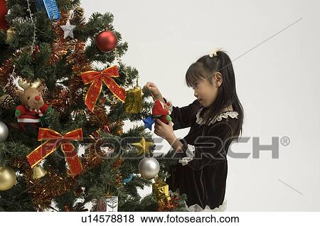 Stock Photo - Girl decorating Christmas tree. Fotosearch