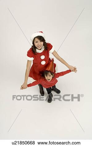 Stock Photo - Mother in Santa outfit standing with daughter. Fotosearch