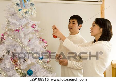 Stock Photography - Couple decorating Christmas tree. Fotosearch