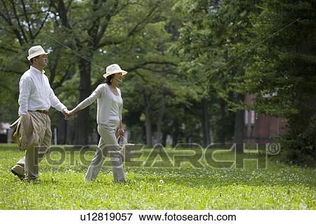 Stock Photo - Mature couple walking holding hands. Fotosearch