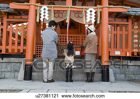 Stock Image - Family praying at shrine. Fotosearch