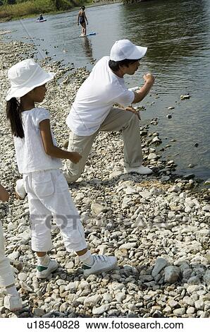 Family skipping stones by river View Large Photo Image Stock Photo - Family skipping stones by river. Fotosearch