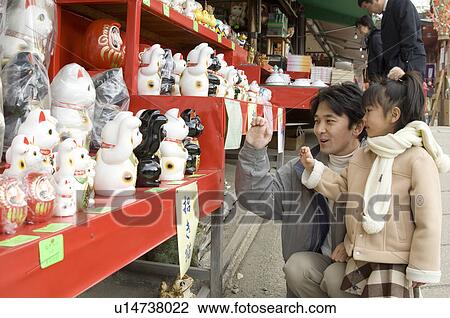 Stock Image - Father and daughter looking at cat statues. Fotosearch