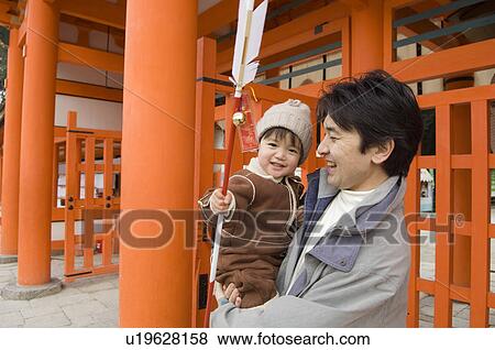 Stock Photo - Father carrying son holding arrow. Fotosearch
