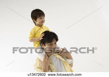 Stock Image - Father carrying son on shoulders. Fotosearch
