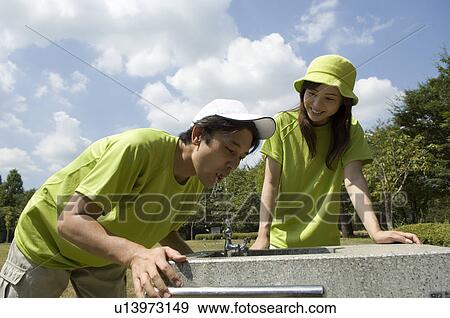 Stock Photo - Husband and wife drinking from water fountain. Fotosearch