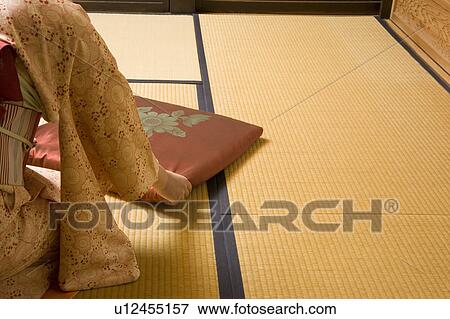 Stock Photo - Woman putting cushion on floor. Fotosearch
