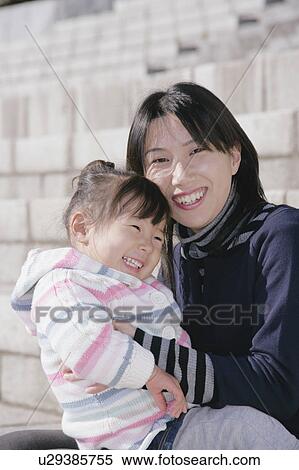 Stock Photography - Mother carrying her daughter. Fotosearch