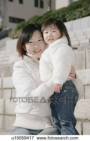 Stock Photo - Portrait of mother sitting with her daughter. Fotosearch