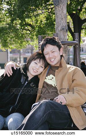 Stock Image - Portrait of young couple sitting. Fotosearch