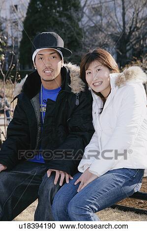 Stock Image - Portrait of young couple sitting. Fotosearch