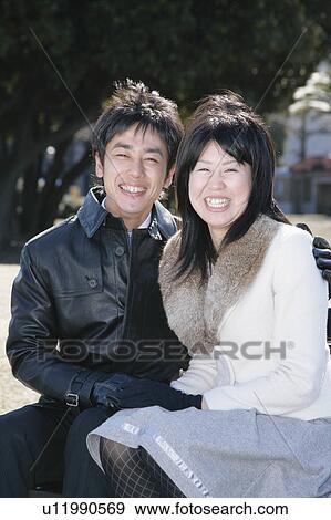 Stock Photo - Portrait of young couple sitting. Fotosearch