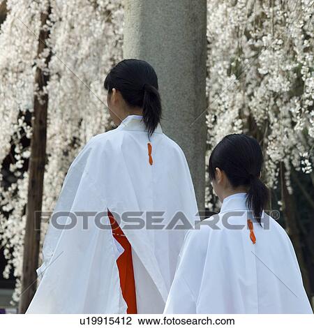 Stock Image - Female attendant walking at shrine. Fotosearch