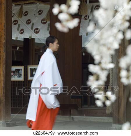 Stock Photo - Female attendant walking at shrine. Fotosearch