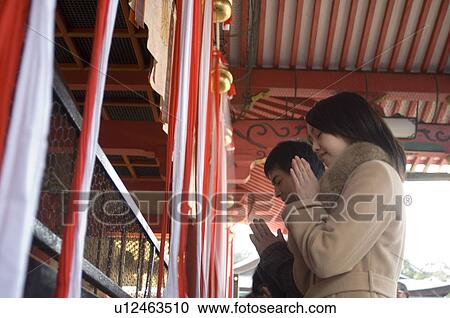 Stock Image - Couple praying at shrine. Fotosearch