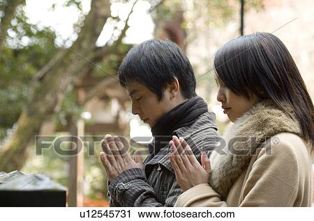 Stock Image - Couple praying at shrine. Fotosearch