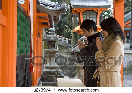 Stock Photo - Couple praying at shrine. Fotosearch