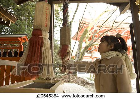 Picture - Girl shaking bell at shrine. Fotosearch