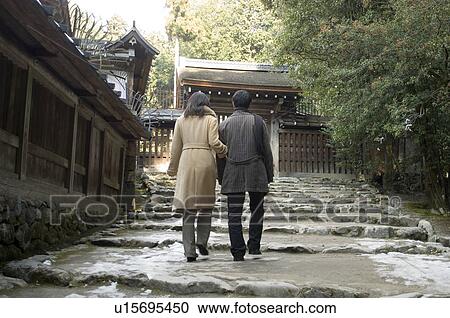 Rear view of couple walking at shrine View Large Photo Image Stock Image - Rear view of couple walking at shrine. Fotosearch