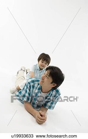Stock Image - Son sitting on father's back. Fotosearch