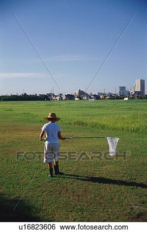 Stock Photograph - Boy catching insects in field. Fotosearch